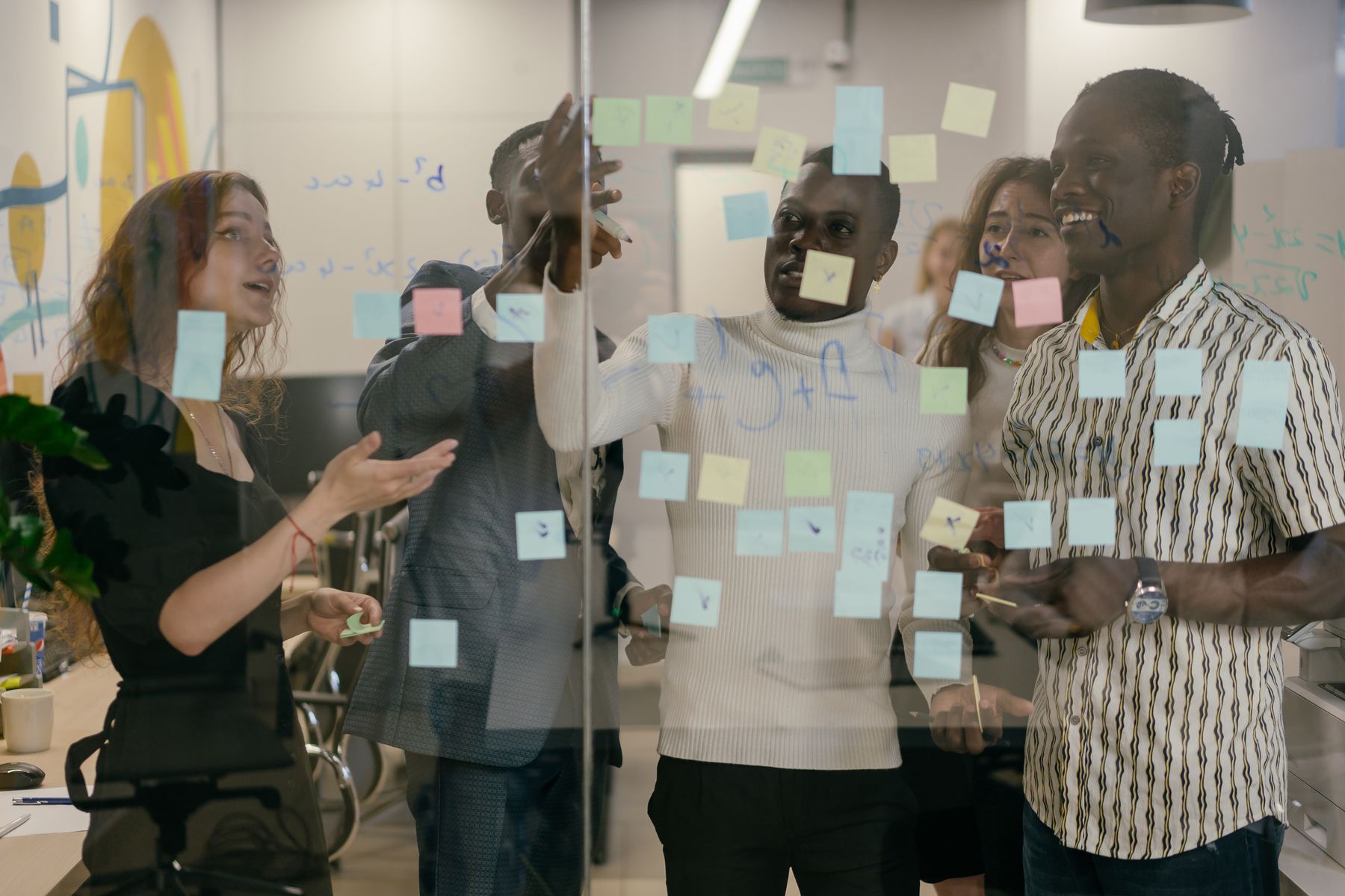 A diverse team collaborating with notes on a glass wall