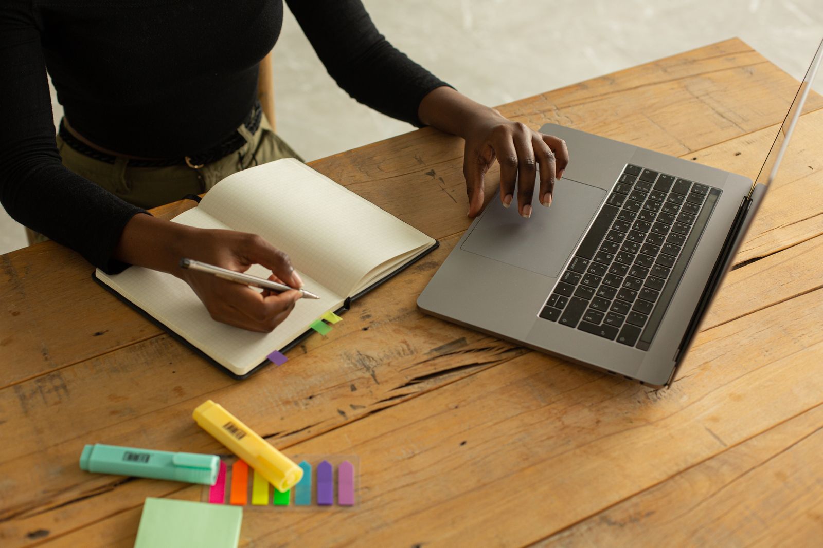 Hands moving between a laptop, notebook, and planning materials
